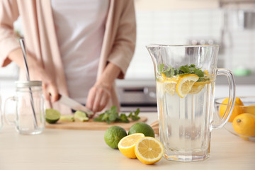 Sticker - Decanter with fresh lemonade in kitchen and blurred woman on background