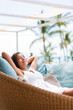 Luxury hotel lifestyle woman relaxing sleeping enjoying luxury sofa on outdoor patio living room. Happy lady lying down on comfortable pillows taking a nap for wellness and health.