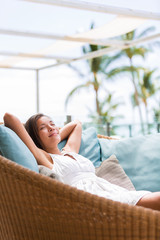 Luxury hotel lifestyle woman relaxing sleeping enjoying luxury sofa on outdoor patio living room. Happy lady lying down on comfortable pillows taking a nap for wellness and health.