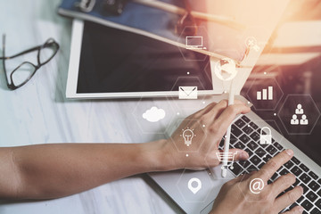 Poster - businessman working with smart phone and laptop computer on wooden desk in modern office with virtual icons interface