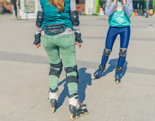 Two girls rollers meet each other in the park. Meeting of friends for roller skating.