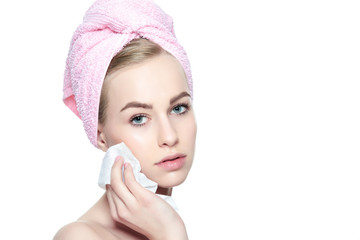 Wall Mural - young blond woman with her hair wrapped in a towel, removing make up. pretty girl with perfect compl