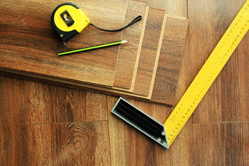 Laminate floor planks and tools on wooden background. Top view.