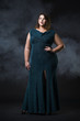 Plus size fashion model in green evening dress, fat woman on black background, overweight female body