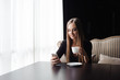 © nagaets - Young woman drinking coffee in a cafe and using a mobile phone