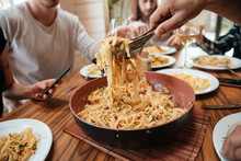 Closeup Of People Eating Pasta On The Kitchen At Home