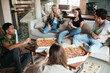 © Drobot Dean - Smiling young friends eating pizza and talking at home