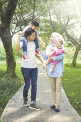 Wall Mural - Asian family walking together in the park