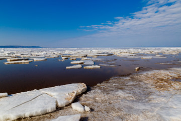 Spring melting of ice on the Volga River against the background of mountains and blue sky