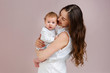 © dinaphoto - Portrait of a beautiful mother smiling with her 3-month-old child, holding hands, side view