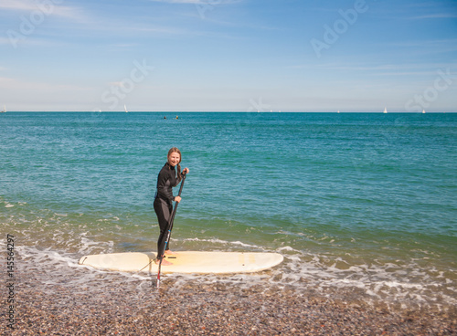 Plakat Młoda kobieta w kombinezon pływać na wstać pokładzie wiosła