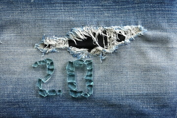 Blue denim vintage jeans in dark color in the scene present the broken tempered grass arrangement the number on the old damaging fabric texture background.