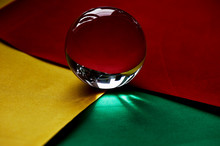 Glass Globe Or Drop Of Water On A Background Of Yellow, Red And Green Velvet Paper.Clean And Shine