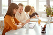 © nenadaksic - Young happy people discussing business standing at the whiteboard in modern light office, beautiful woman sitting at the table at forefront