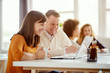 © nenadaksic - Young happy people discussing business standing at the whiteboard in modern light office, beautiful woman sitting at the table at forefront