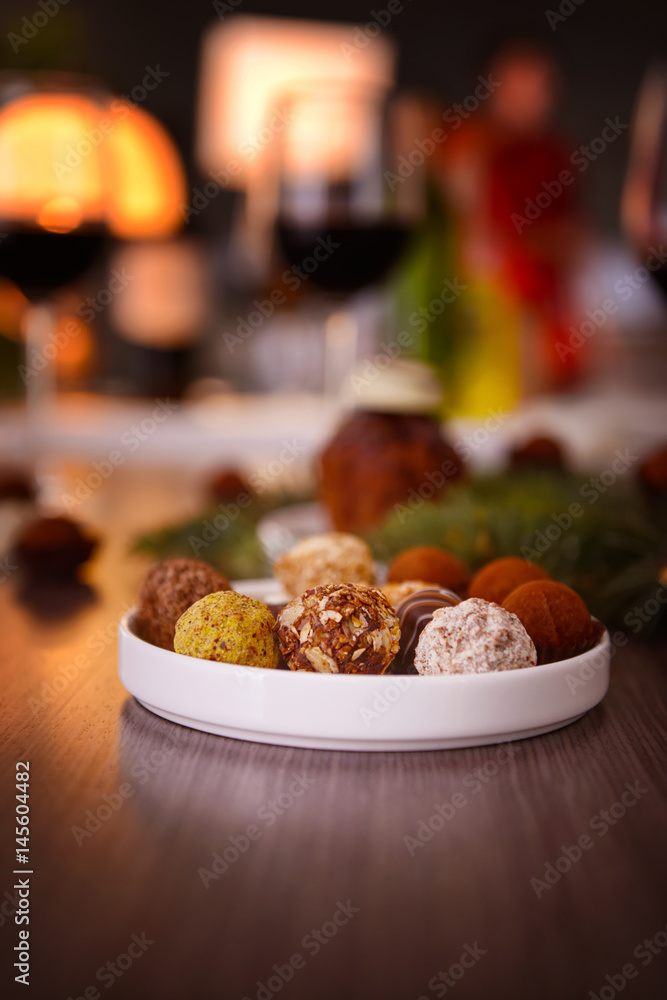 Delicious chocolates in plate on wooden table closeup