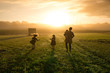 © Sarah Rypma - Mother and daughters playing in field during sunset
