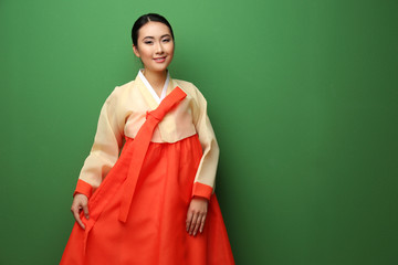 Beautiful young woman dressed in traditional clothing on green background