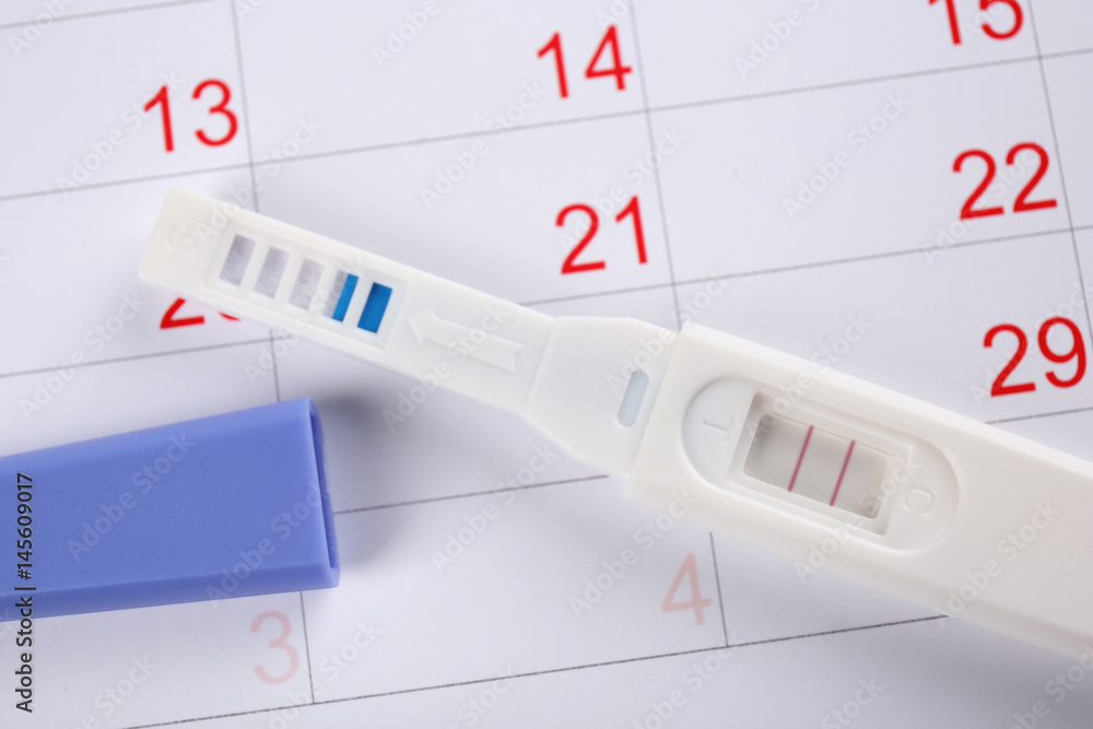 Pregnancy test on calendar background