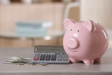 Poster - Saving electric power concept. Ceramic piggy bank with calculator and money on table