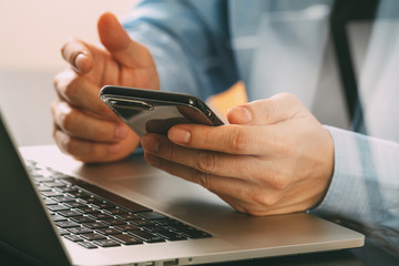 Poster - close up of businessman working with mobile phone and laptop computer on wooden desk in modern office