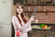 © slavonstok - woman is standing in the kitchen near the table with fresh vegetables. girl is holding a knife and a tomato in her hands