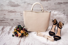 Fashionable Concept. Light Bag, Black Shoes And Flowers On A White Fur
