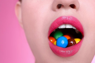 Wall Mural - Face of beautiful young woman with candies on color background, closeup