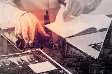 Poster - close up of businessman working with smart phone and digital tablet and laptop computer  on wooden desk in modern office with London city exposure