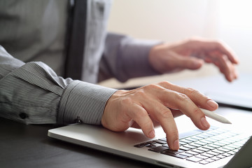 Poster - close up of businessman working with mobile phone and stylus pen and laptop computer  on wooden desk in modern office