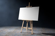 Wooden Artist Easel with White Mock Up Canvas in the volumetric light. 3d Rendering