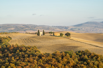 chapel in the middle of plowed fields in autumn tuscany