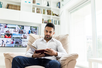 Wall Mural - Young confident man reading book at modern home