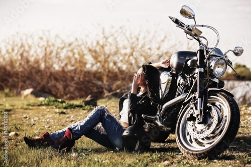 piekna-brunetka-siedzaca-na-ziemi-oparta-o-motocykl