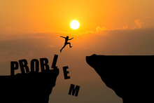 Man Jumping Over Problem Text Over Cliff On Sunset Background,Business Concept Idea