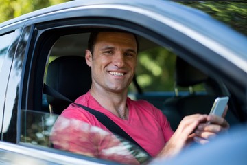 Portrait of smiling man using mobile phone in car