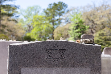 headstone in jewish cemetery with star of david and memory stones