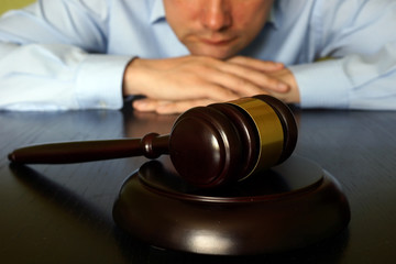 Wall Mural - Justice concept. Man is sitting at the table opposite gavel.