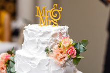 A Multi Level White Wedding Cake On A Silver Base And Pink Flowers On Top