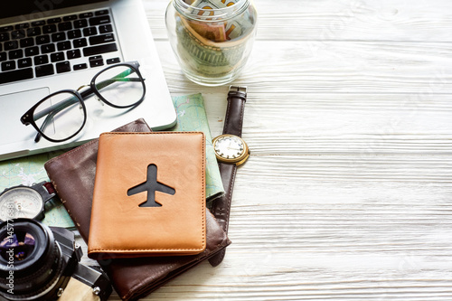 Obraz na płótnie travel and wanderlust concept, planning summer vacation, space for text jar with money map compass photo camera glasses wallet watch laptop on white wooden background time to travel