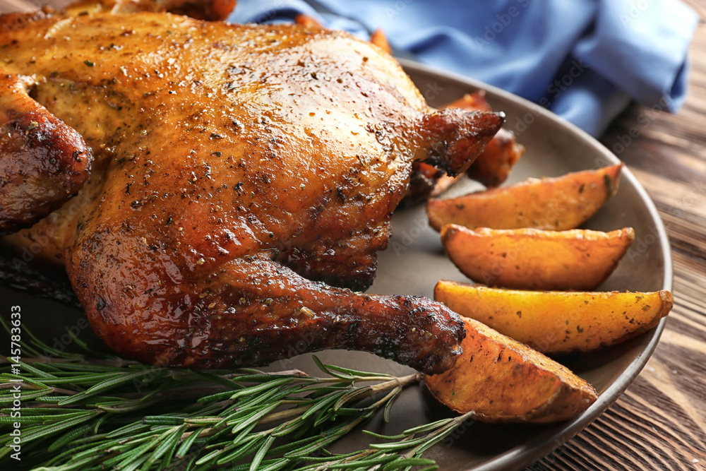 Plate with roasted beer can chicken on table, closeup