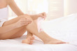 © Africa Studio - Young woman depilating legs with wax sitting on bed