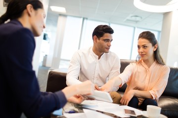 Wall Mural - Young business people discussing over documets at office