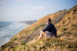 Young man, boy sitting on the cliff in San Diego, California. Sunset cliff. Meditation
