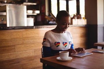 Wall Mural - Happy woman using digital tablet while having coffee