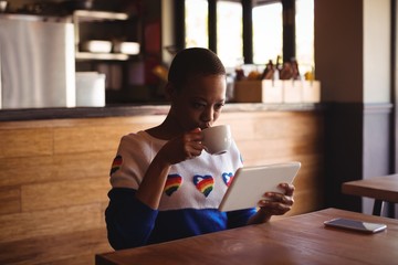 Wall Mural - Woman using digital tablet while drinking coffee