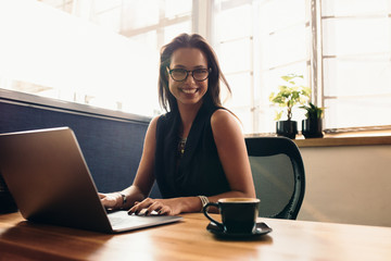 Young woman working on laptop computer in office.