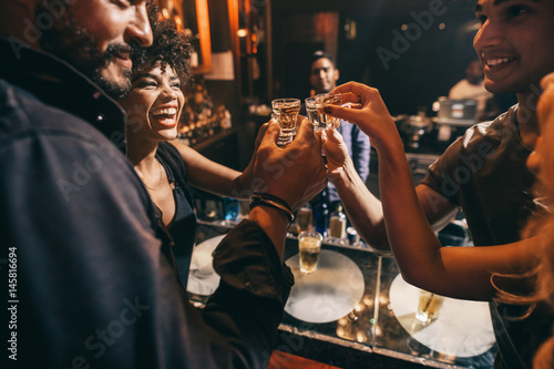 Fotografía Friends toasting each other with shots of vodka