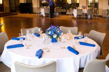 White tablecloth with wineglass, blue tissue napkin. Table set up