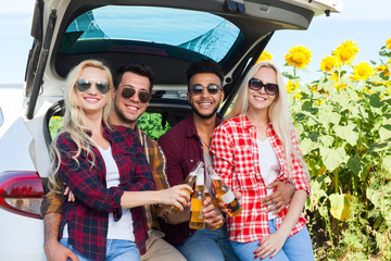 Sticker - Friends drinking beer toasting clink bottles sitting in car trunk outdoor countryside, happy smile people group summer sunflower field